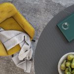 Photo d'ambiance d'une salle à manger avec une table et des chaises. Les piètement sont en acier laqué noir avec un dossier et une assise en tissu jaune. Les chaises sont pivotantes.