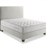 Photo présentant un lit composé d'un matelas en latex blanc de hauteur : 32, ainsi qu'une tête de lit en tissu blanc crème.