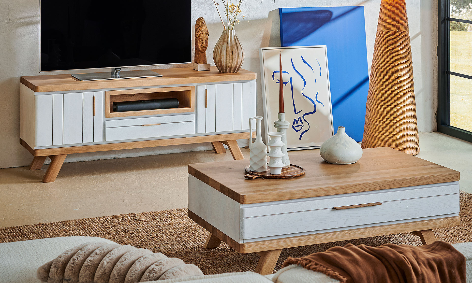 Photo d'ambiance présentant un salon avec un meuble TV et une table basse. Avec une finitions bois chêne massif peinte en partie en blanc mat.